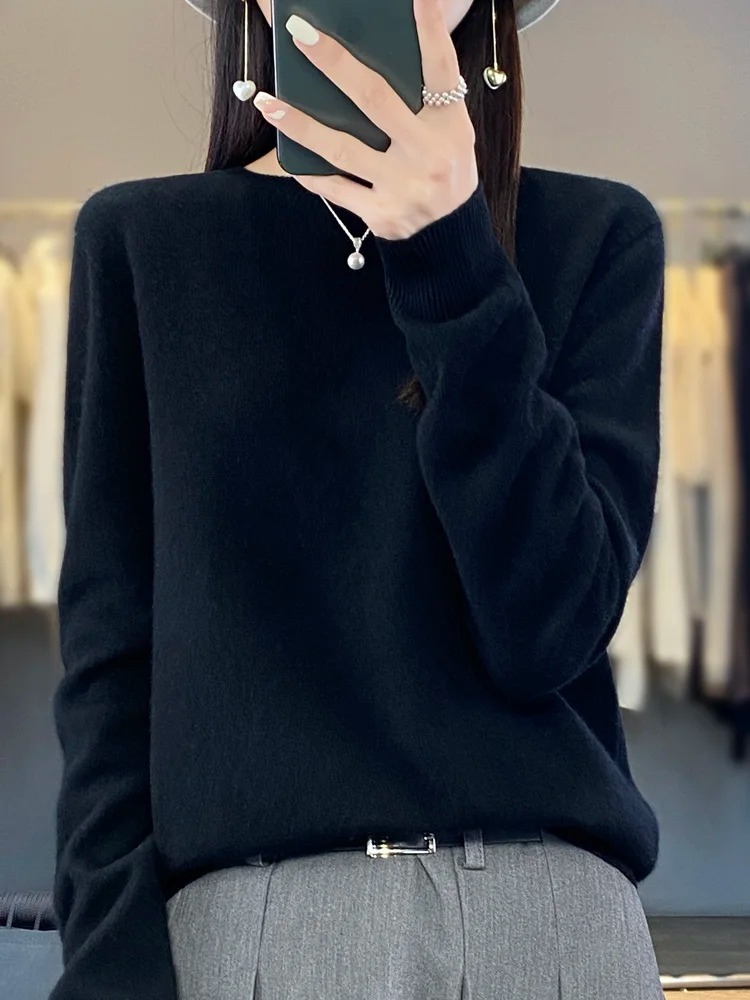 Black plain jumper worn tucked into grey trousers.
