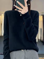 Black plain jumper worn tucked into grey trousers.
