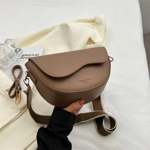 Taupe structured shoulder bag held above pale fabric.