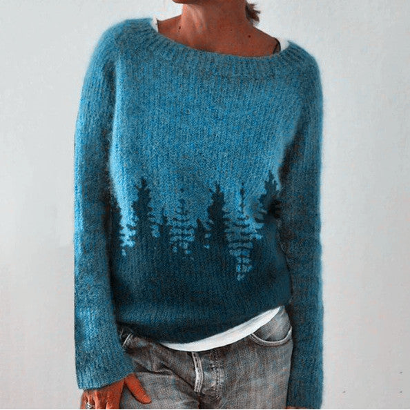 Blue knit jumper with dark tree silhouettes and a wide neckline.