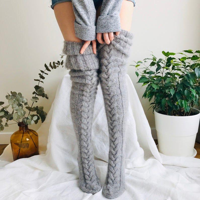 Grey thigh-high knitted socks with cable patterns and folded ribbed tops.