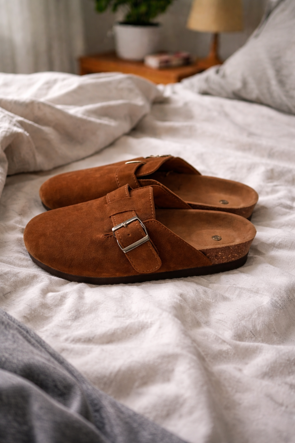 Brown open-back clogs with wide straps and metal buckles.