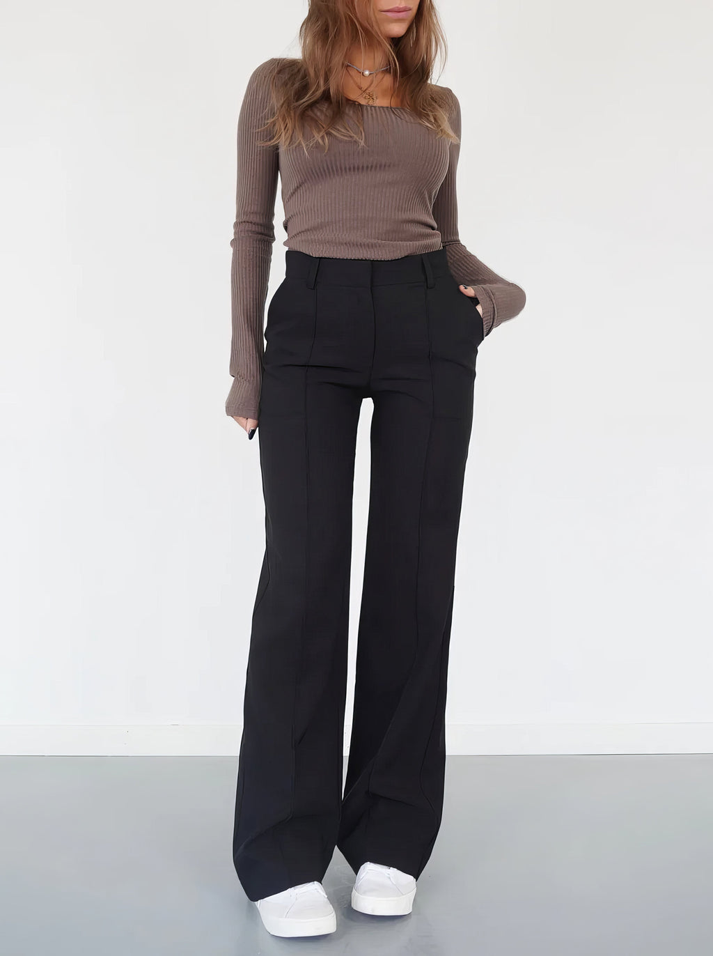 Black trousers worn front-on, with one hand at the side pocket.