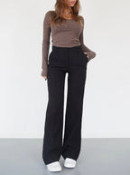 Black trousers worn front-on, with one hand at the side pocket.