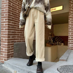 Beige trousers with turned-up hems, worn outdoors.