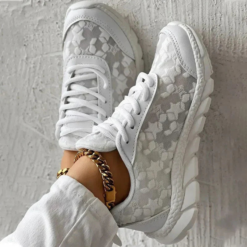 Top view of white lace-up trainers with floral mesh-effect panels.