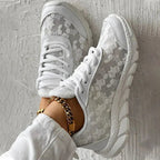 Top view of white lace-up trainers with floral mesh-effect panels.