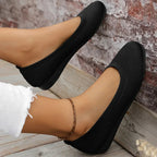 Black flat shoes shown worn from above.