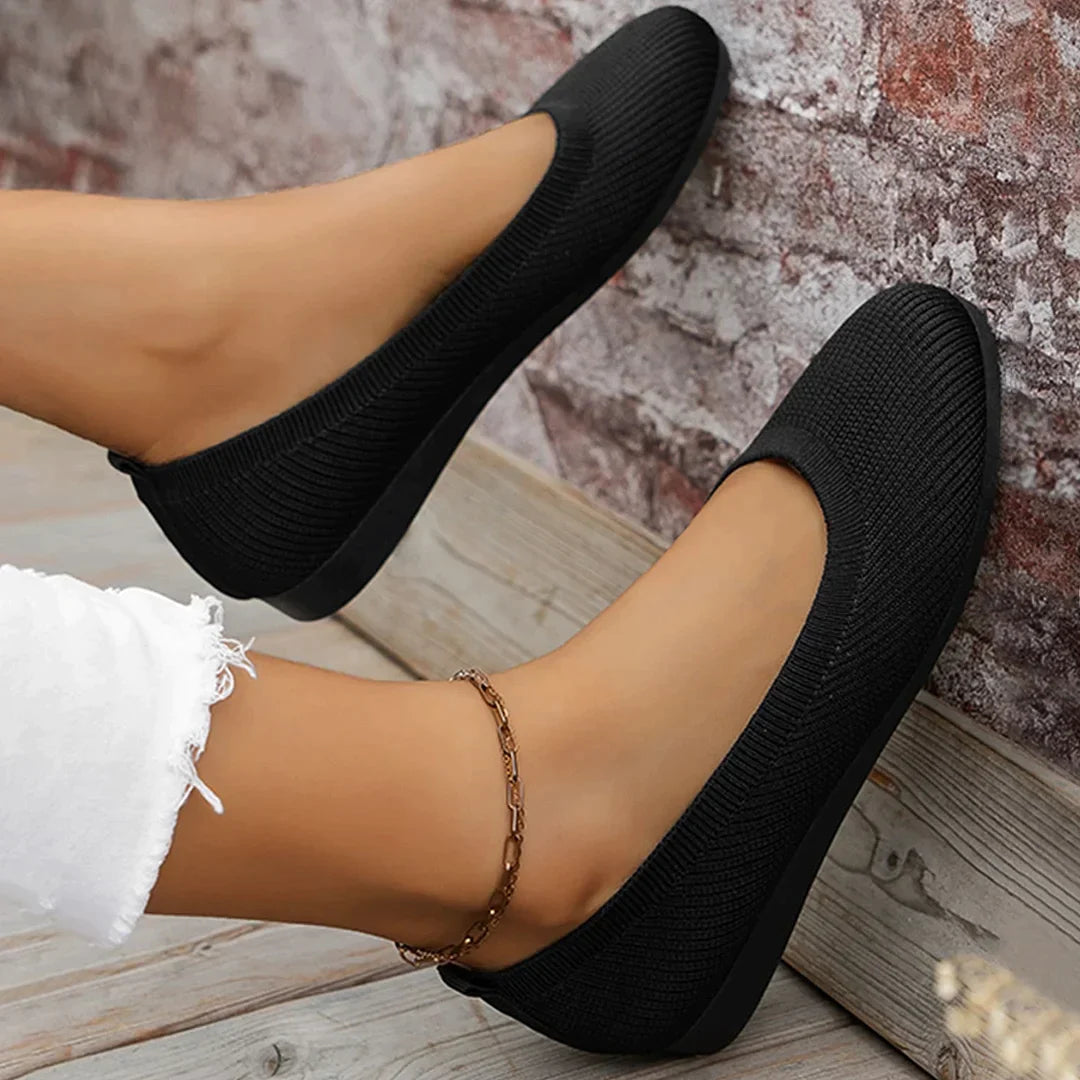 Black flat shoes shown worn from above.
