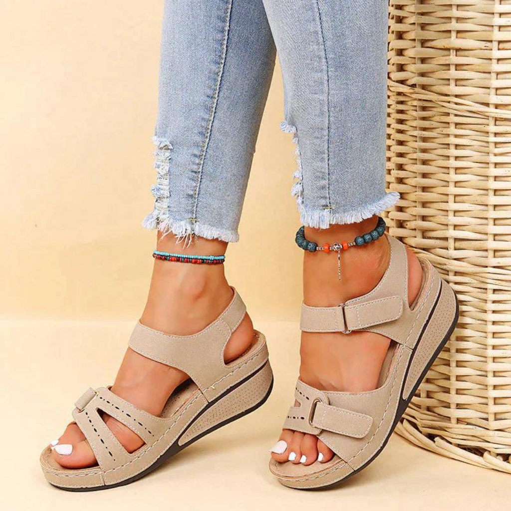 Beige wedge sandals worn with cropped blue jeans.