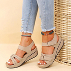 Beige wedge sandals worn with cropped blue jeans.