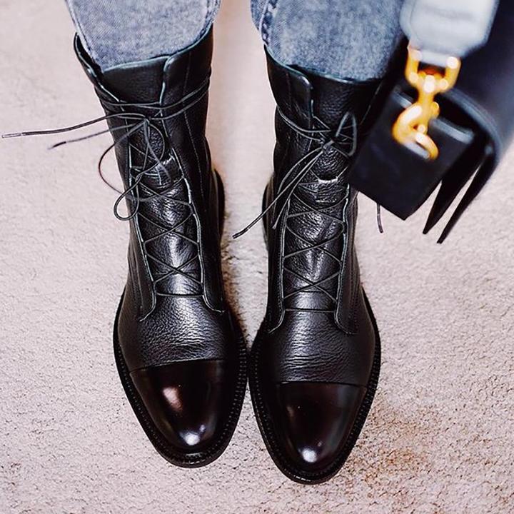 Black ankle boots worn with jeans, showing textured uppers and glossy toes.