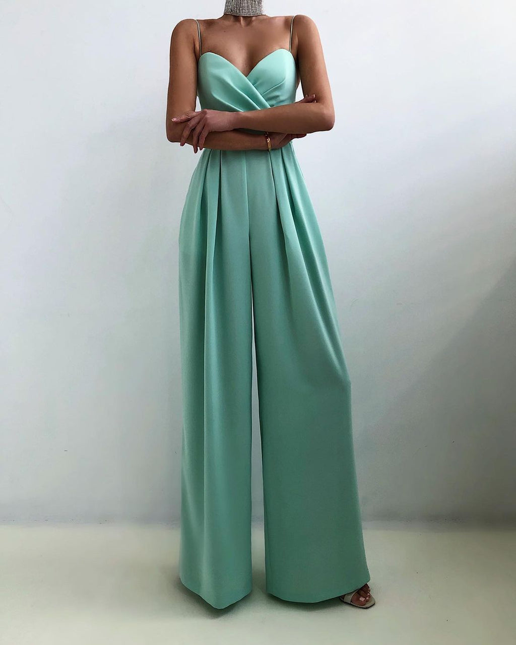 Turquoise jumpsuit with a folded neckline and slim straps.