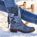 Blue knit-cuff boots worn with jeans on a snowy surface.
