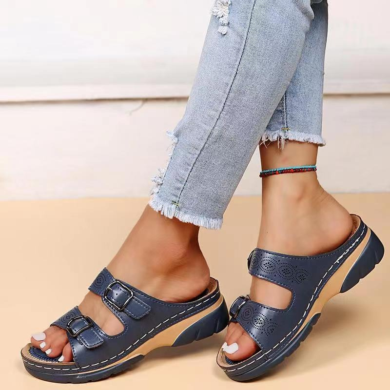 Dark blue buckle slide sandals shown on feet with cropped jeans.