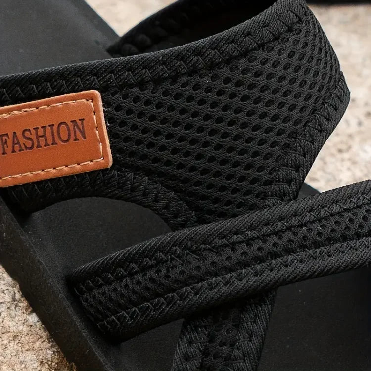 Close view of black mesh straps, stitched edges and a patch reading Fashion.