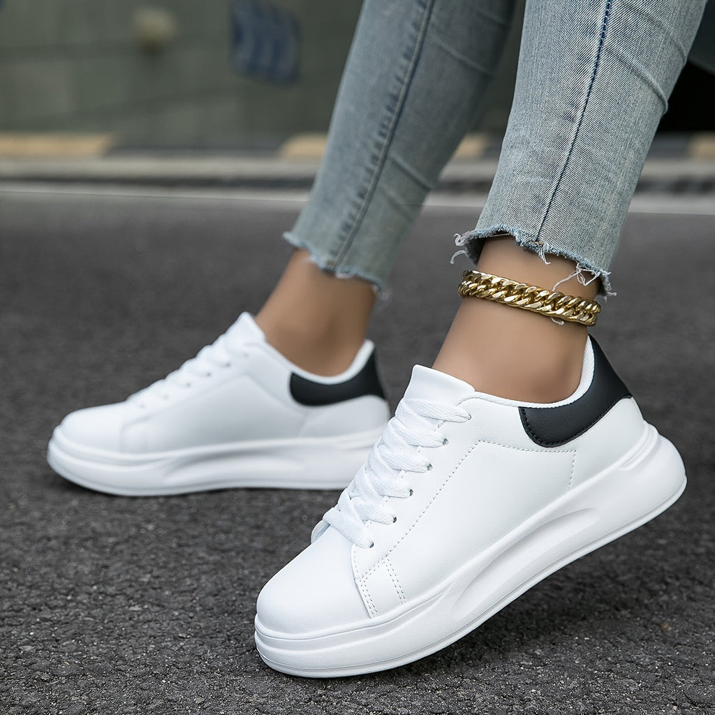 White trainers with black heel panels and flat white laces.