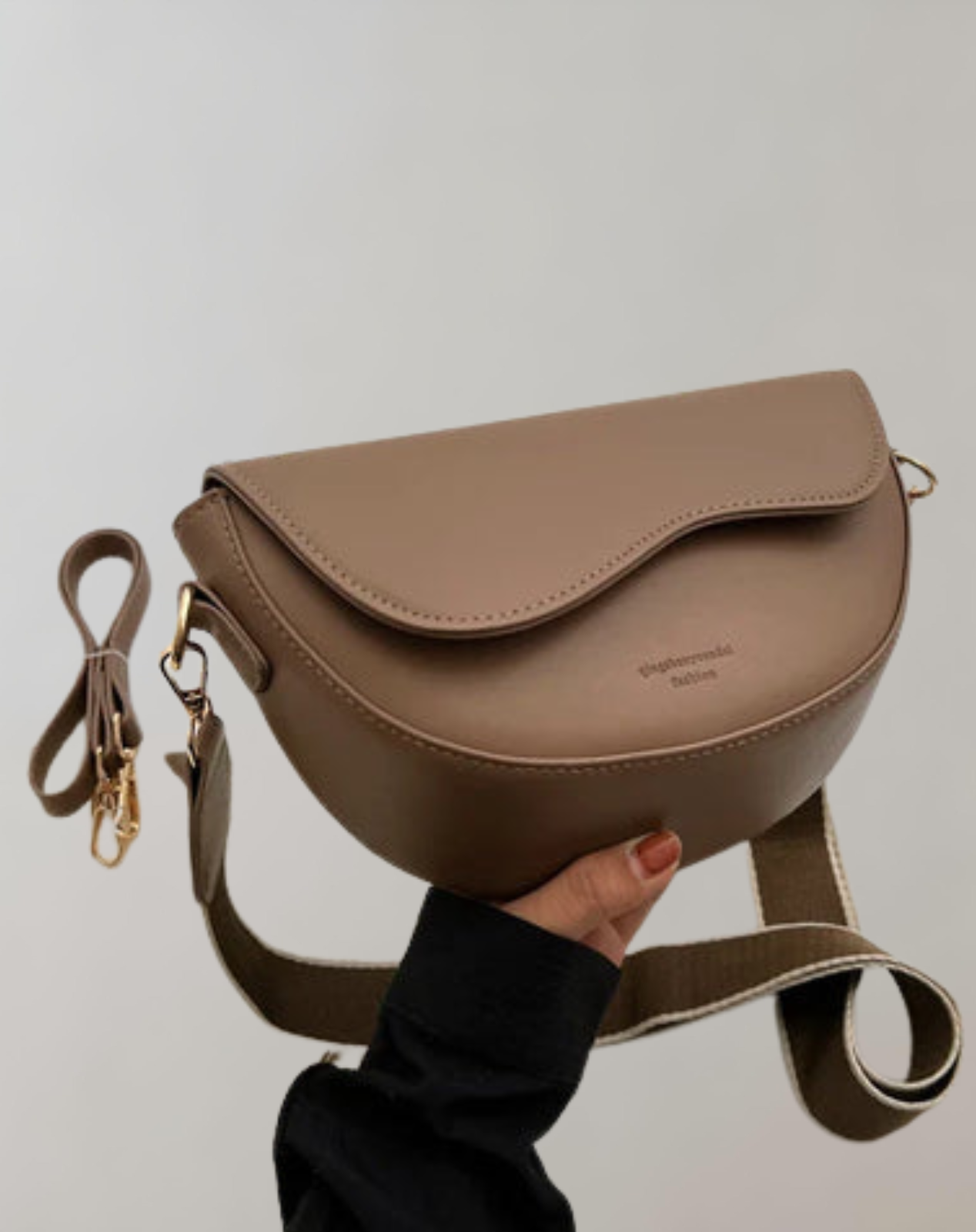 Taupe shoulder bag with a curved flap and a wide adjustable strap.