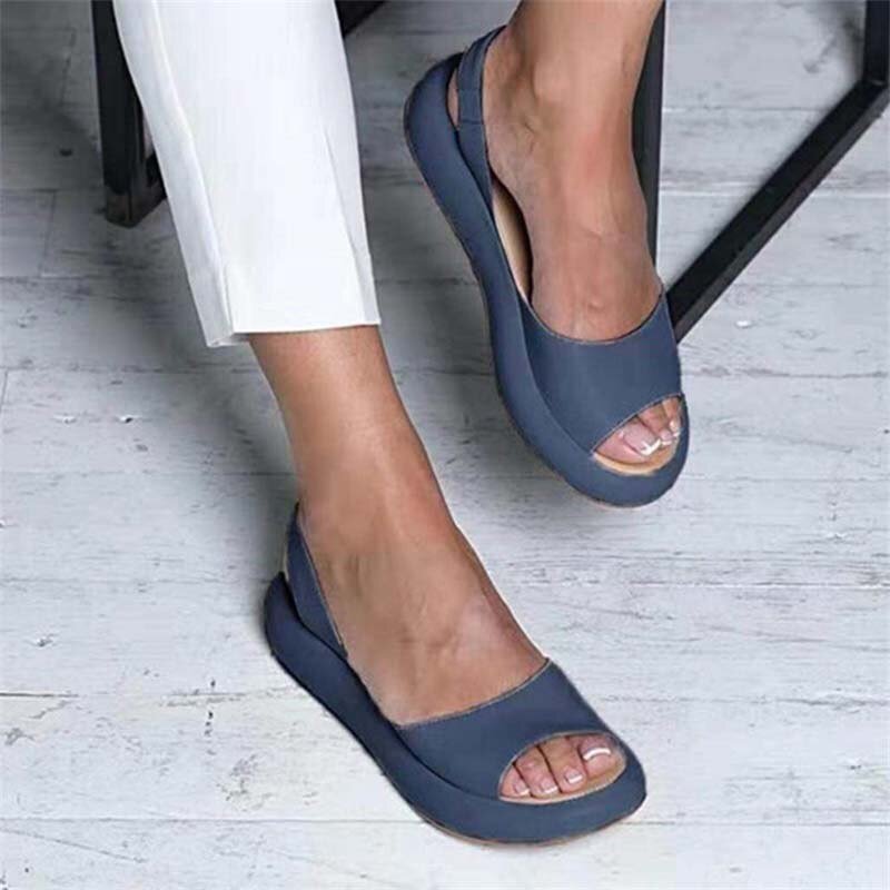 Blue Keliso open-toe sandals worn with white trousers.