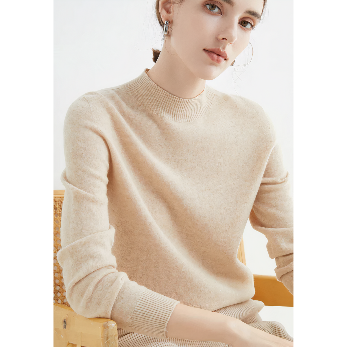 Beige jumper viewed from an angle, with hands resting in front.