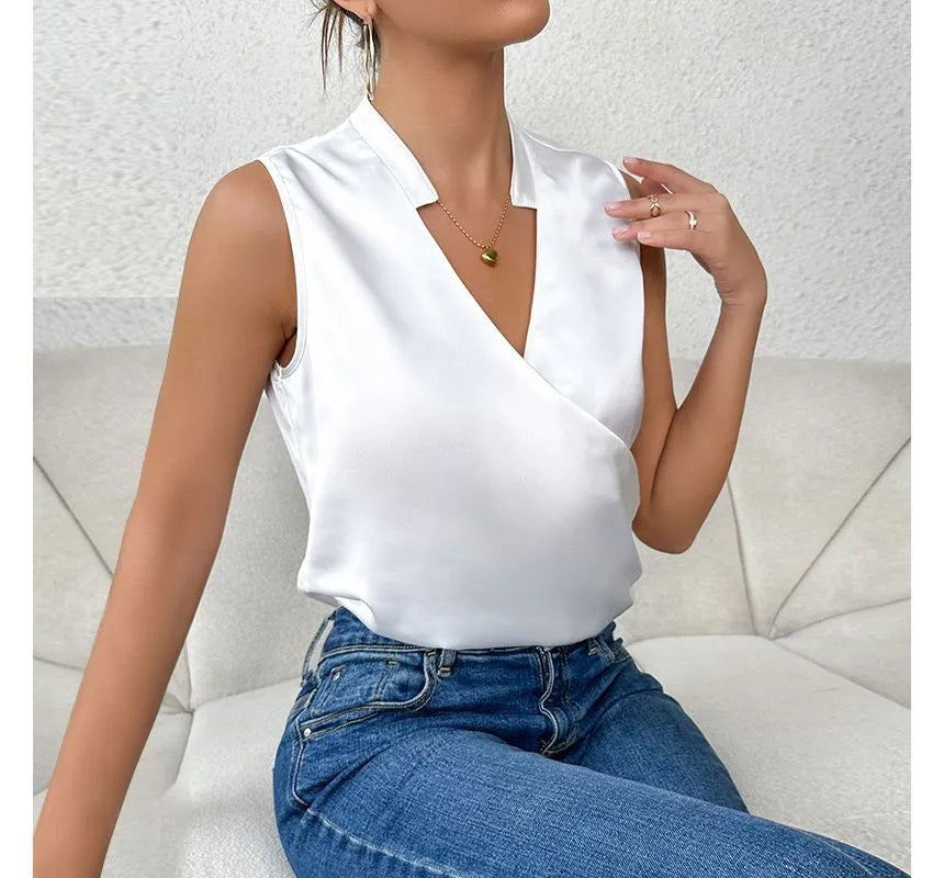 White crossover top worn with jeans while seated.