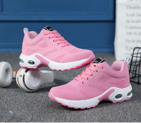 Pink trainers displayed beside a clock and headphones.