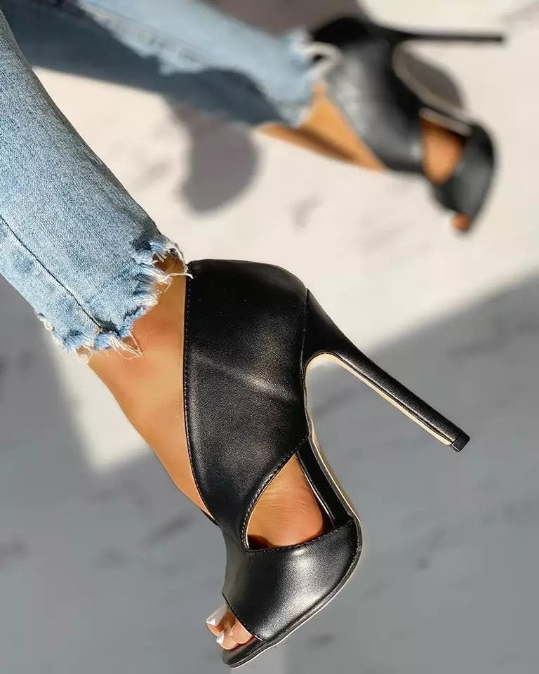 Black peep-toe shoe shown from the side, with a slim high heel and curved cutout.