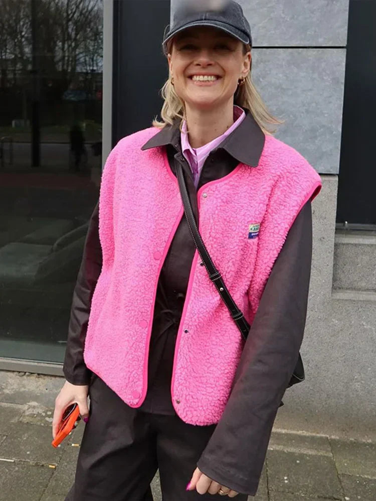 Bright pink textured gilet with front pockets worn over a dark shirt.