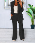 Black lapel jacket and matching trousers, worn with a white top.