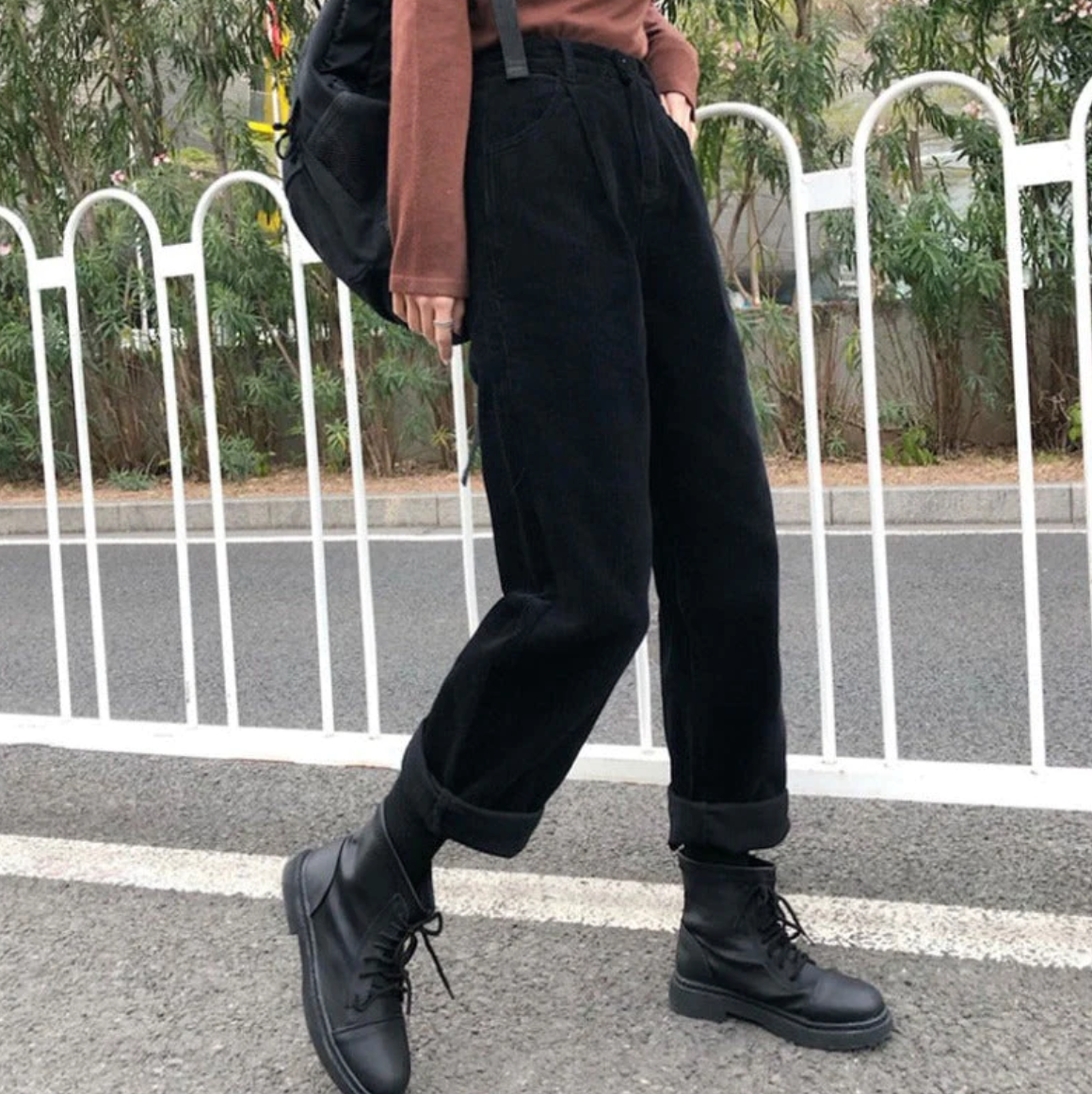 Black trousers showing the loose leg shape and rolled hems.