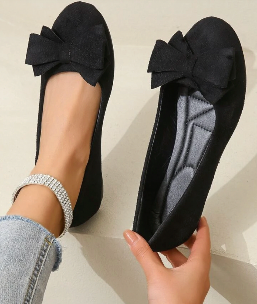 Black flat held to show the shaped insole and bow detail.