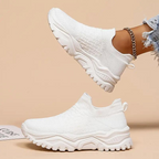 White slip-on trainers with textured uppers and deep-grooved white soles.