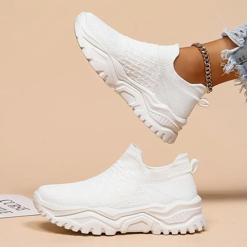 White slip-on trainers with textured uppers and deep-grooved white soles.