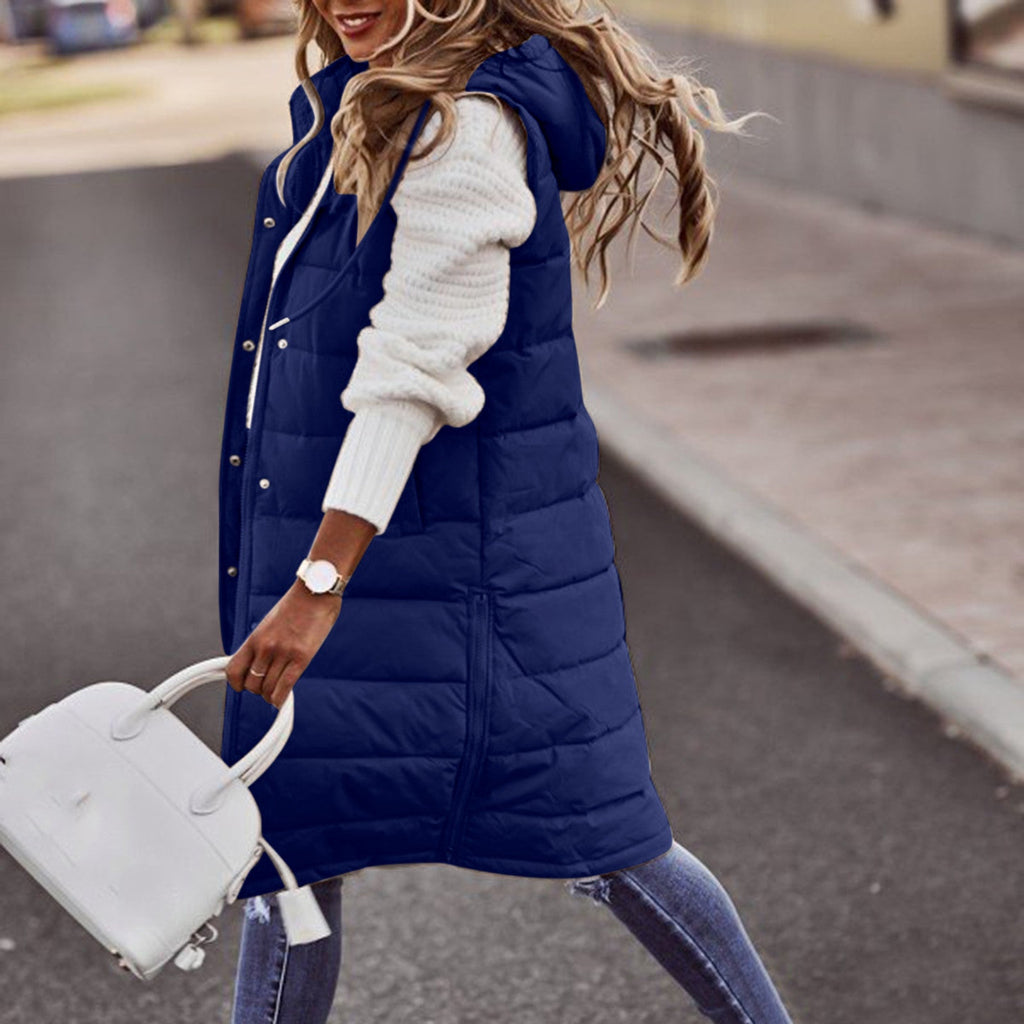 Navy blue long quilted gilet worn over a white jumper.