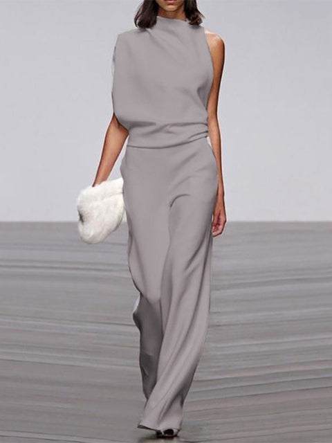 Grey jumpsuit with a gathered waist and long wide legs on a model.