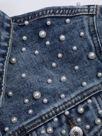 Detail of round white beads in different sizes on blue denim.