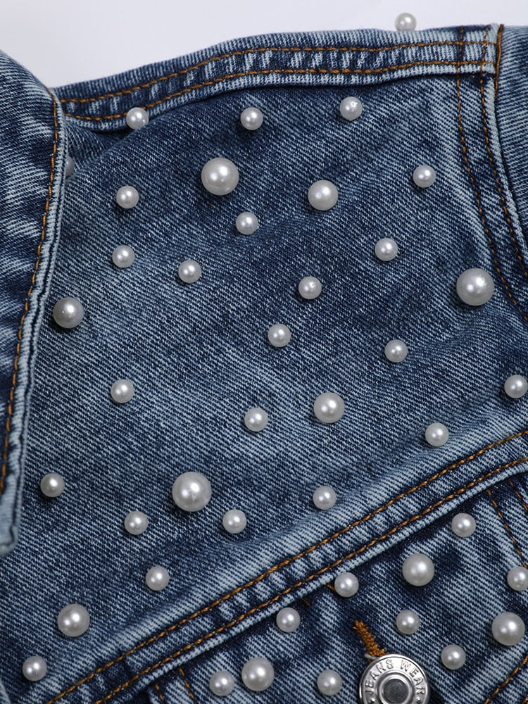 Detail of round white beads in different sizes on blue denim.