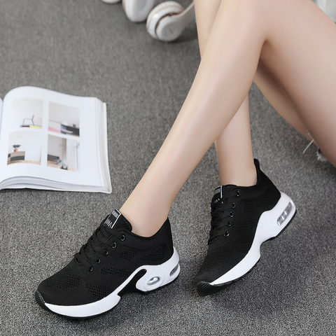 Black trainers with white soles shown beside a magazine and headphones.