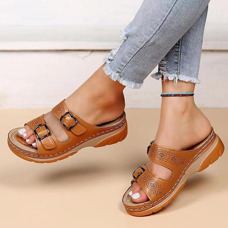 Brown buckle slide sandals worn with cropped jeans.