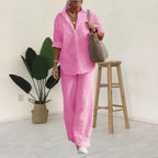 Pink shirt and trouser set shown against a pale indoor background.