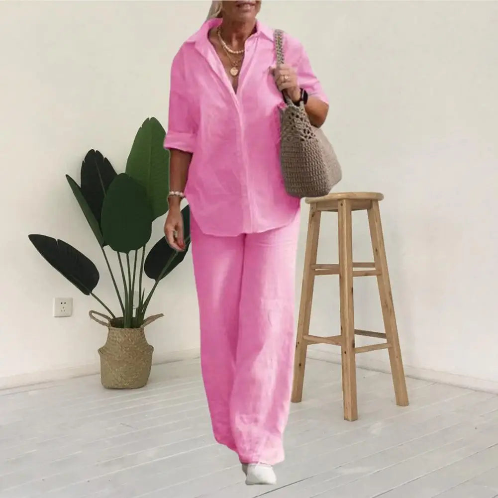 Pink shirt and trouser set shown against a pale indoor background.