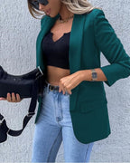Green blazer worn over a black top and jeans.