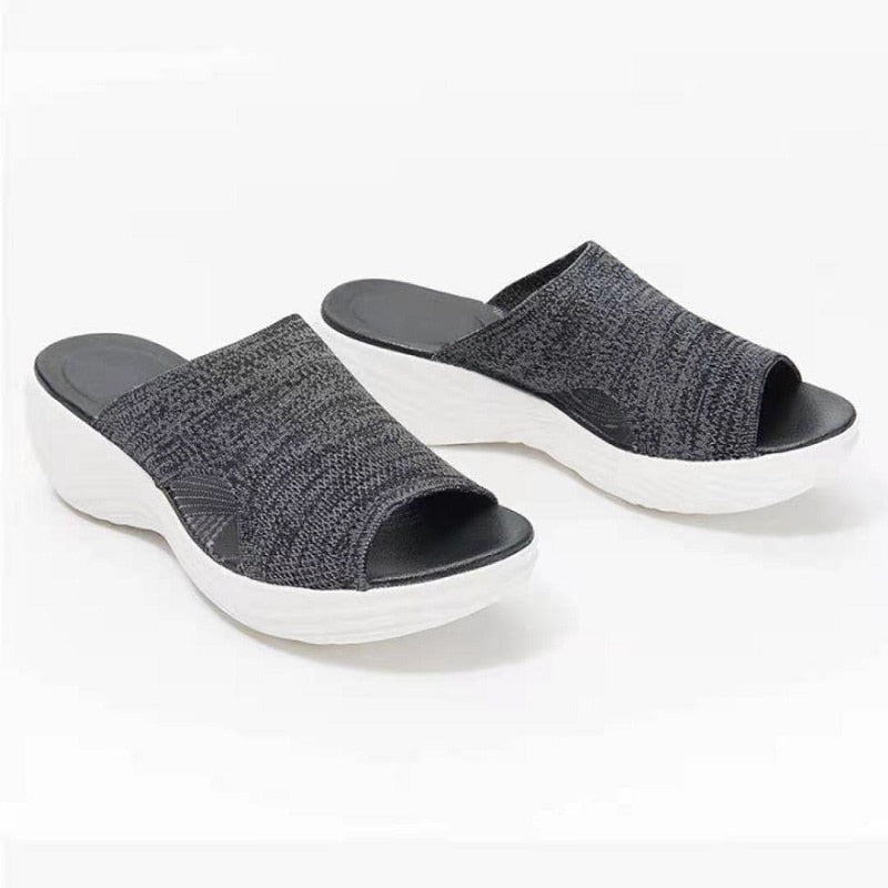 Pair of black slide sandals with white soles.
