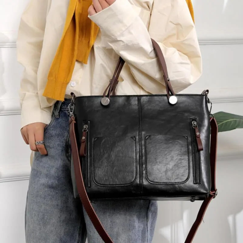 Black handbag carried by its brown handles.