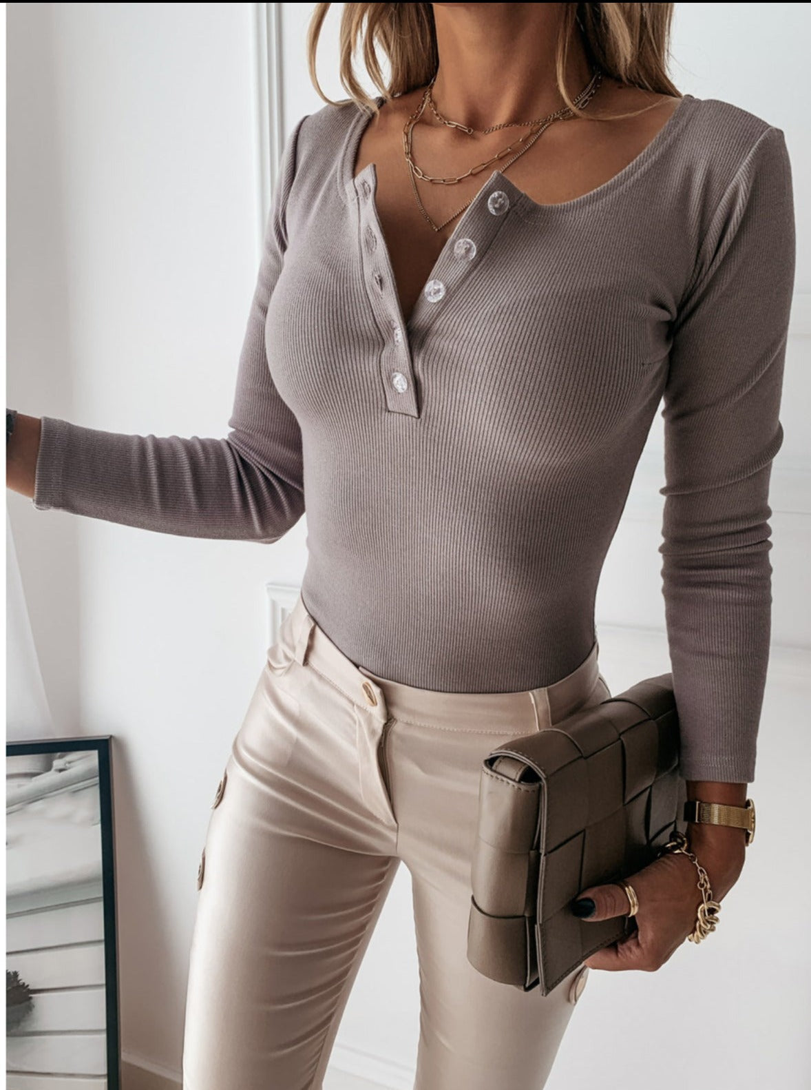 Taupe long-sleeved ribbed top worn with pale trousers.