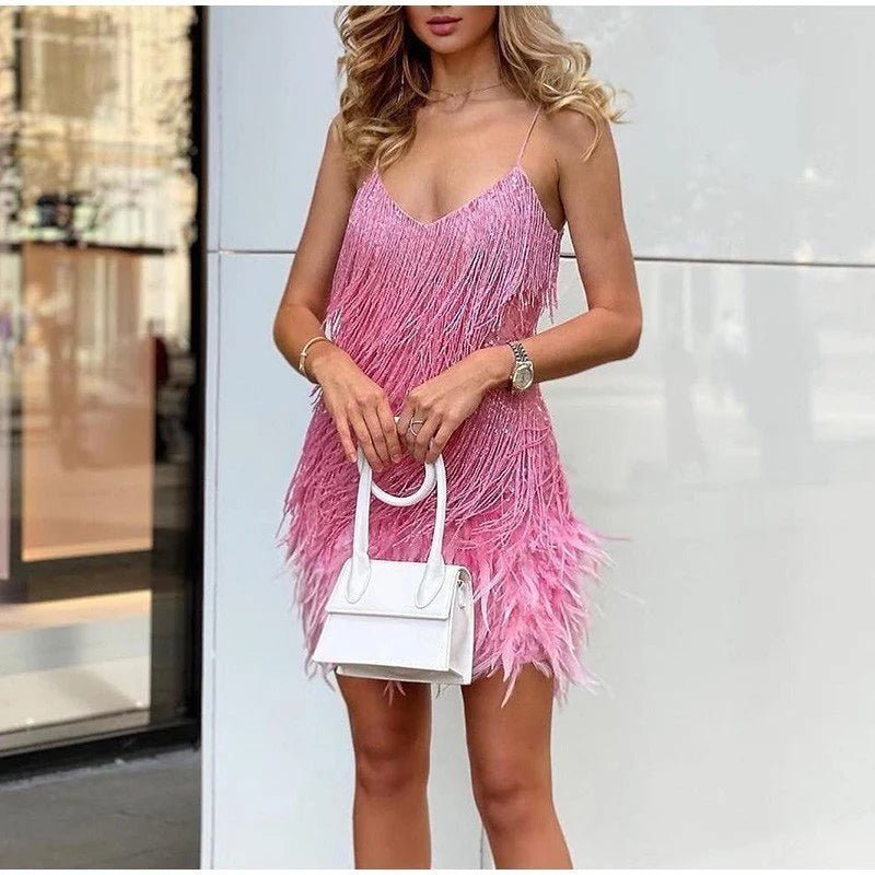 Pink sequin-fringe dress with a feather hem, worn outdoors with a small white handbag.