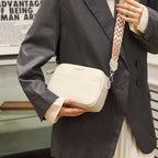 Beige shoulder bag carried with a dark blazer.