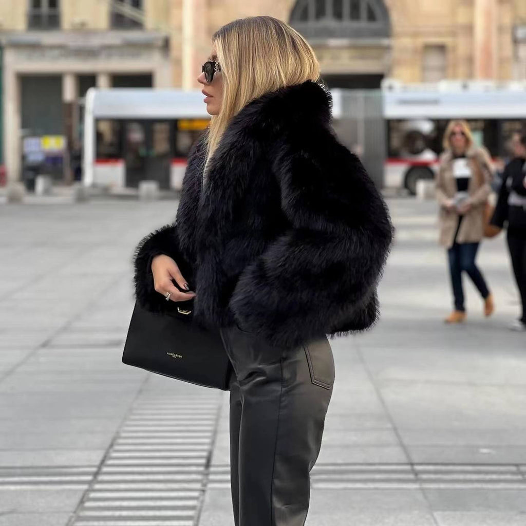 Side view of a black short jacket with long sleeves and a broad collar.