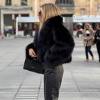 Side view of a black short jacket with long sleeves and a broad collar.