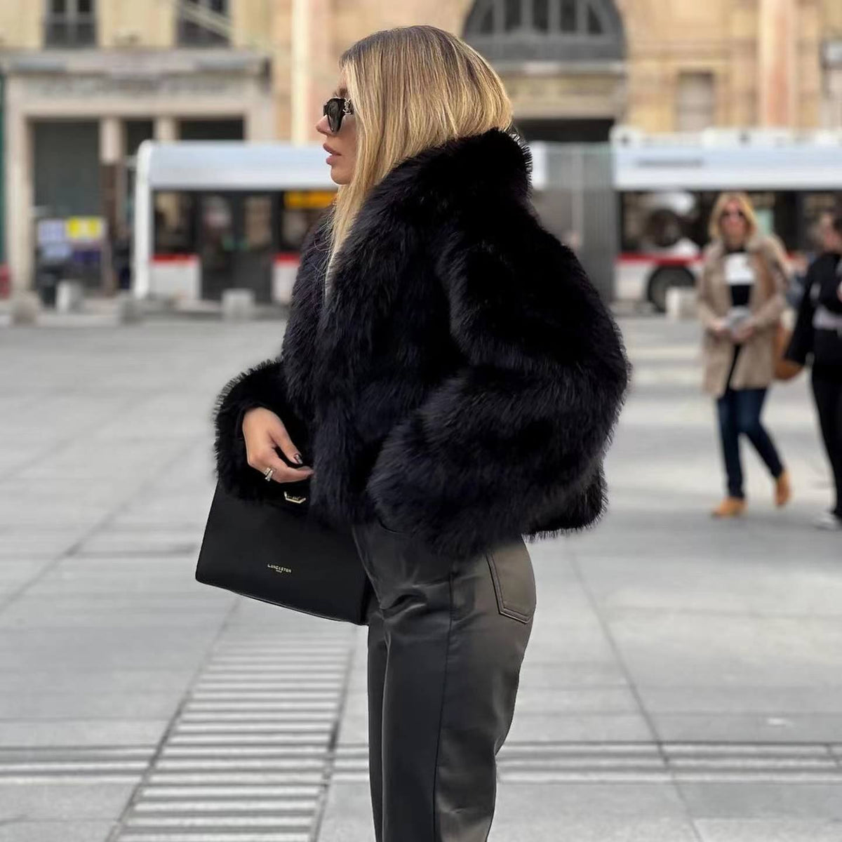 Side view of a black short jacket with long sleeves and a broad collar.